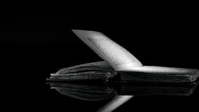 immagine-bianco-e-nero-ad-alto-contrasto-di-vecchio-libro-su-superficie-riflettente-nera-52150930